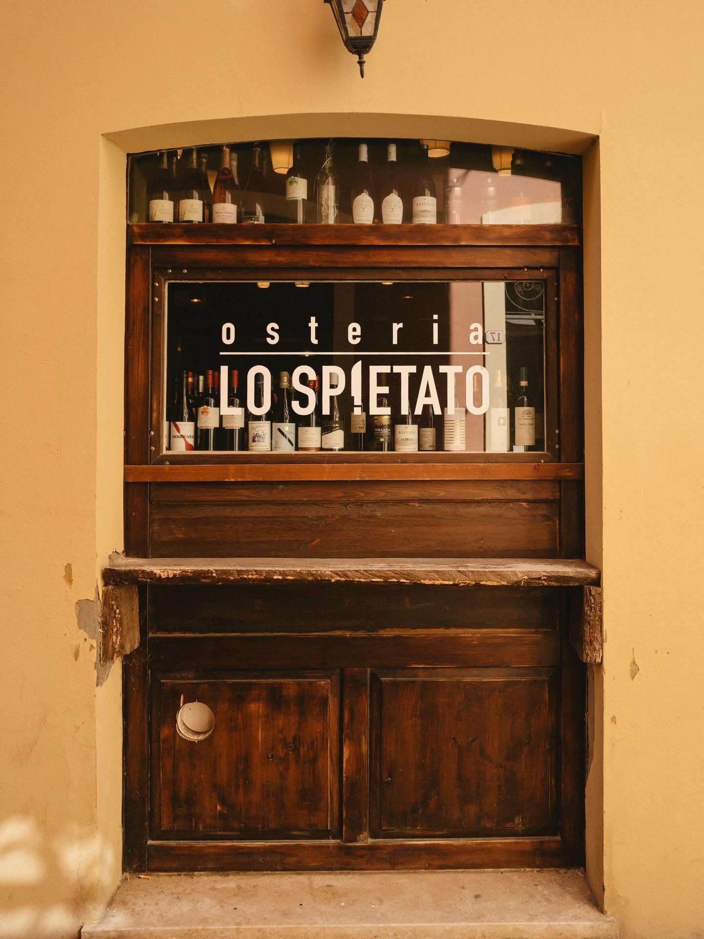 Ingresso dell'osteria con vetrina in legno e bottiglie di vino